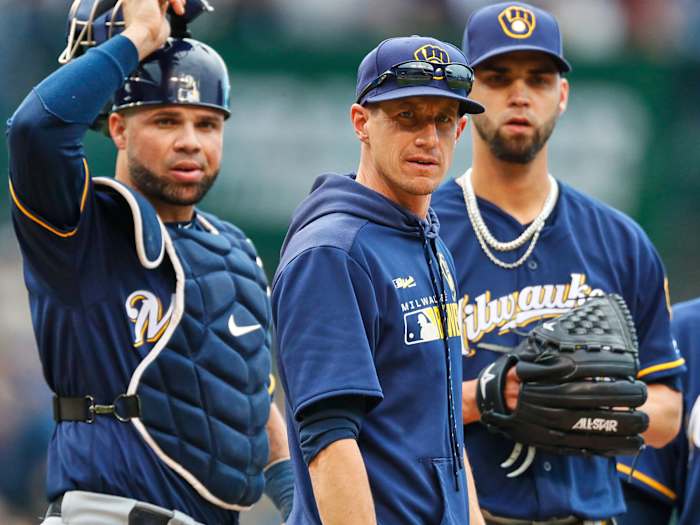 Craig Counsell standing on the mound with two players